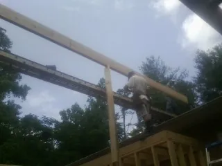 Carpenter setting a ridge beam over a new addition frame — Ice Dam Removal by Roofing Brothers in Harlan