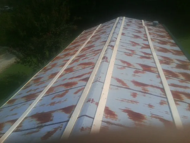 Rusted metal roof panels with new wood purlins before replacement — Storm Damage Roof Repair in Harlan by Roofing Brothers