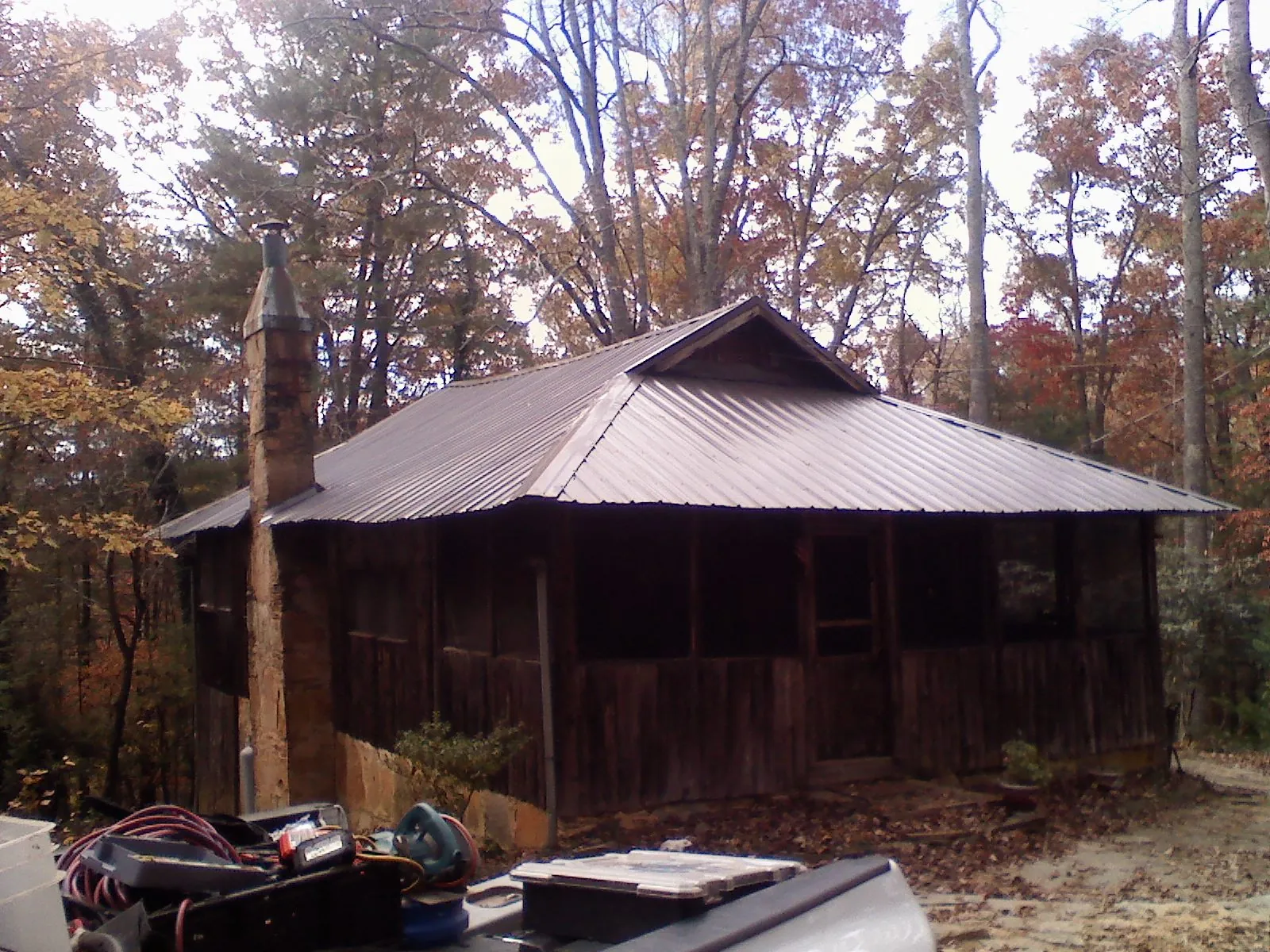 Brown metal hip roof on an old cabin with a stone chimney in Harlan